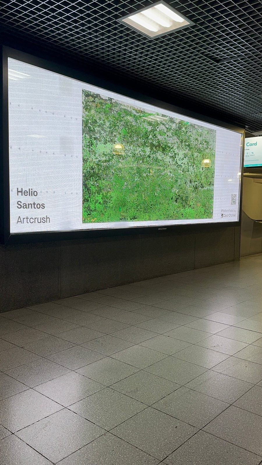 Wide screen in a Brussels underground passage showing a green pixel landscape